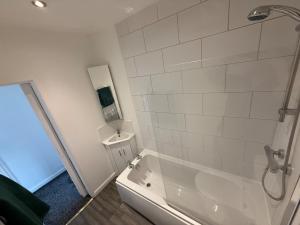 a white bathroom with a tub and a sink at Cheap Grantham Town Centre Terrace House in Lincolnshire