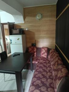 Zimmer mit Sofa, Tisch und Uhr in der Unterkunft Апартамент за гости Централ in Malko Tŭrnovo