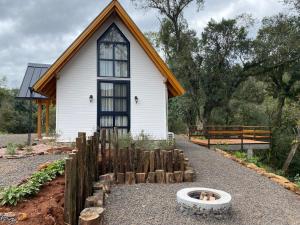 VideiraCabana Vale das Bromélias的前面有一只狗的小白色房子