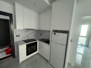 a white kitchen with white cabinets and a refrigerator at RbNb Shengjin in Shëngjin