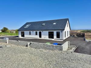 a white house with a black roof on a driveway at Lewis Living in Isle of Lewis