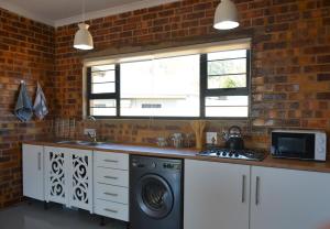 a kitchen with a washing machine and a brick wall at Dullight Self Cater Cottage in Dullstroom