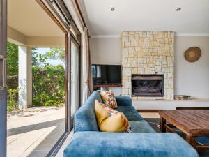 LinksView at Pezula في كنيسنا: غرفة معيشة مع أريكة زرقاء ومدفأة