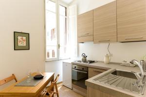 - une cuisine avec des placards en bois, une table et un évier dans l'établissement CS Cosy Termini Studio, à Rome
