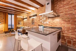 una cocina con una pared de ladrillo y una barra con taburetes en Sweett - Gallery Poble Sec, en Barcelona