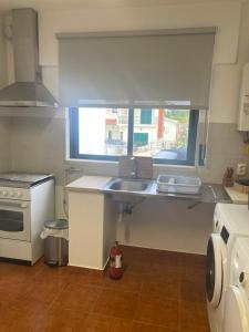a small kitchen with a sink and a window at Rolo House in Nazaré