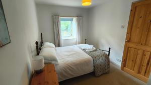 une chambre avec un lit avec des draps blancs et une fenêtre dans l'établissement Mews Cottage, à Middleton in Teesdale