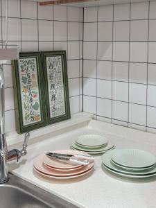 a pile of plates sitting on a counter next to a sink at 홍대 풀하우스!신축!무료주차!엘베 남들과다른 특별한공간 in Seoul