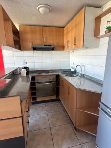 a kitchen with wooden cabinets and a sink at Departamento vista al mar in La Serena