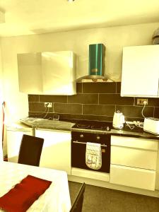 cocina con fogones, armarios blancos y mesa en High class accommodation, en Bury