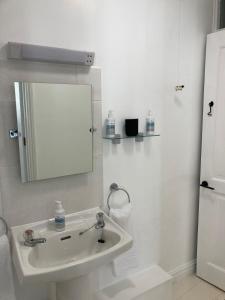 a white bathroom with a sink and a mirror at Pelican House in Bridport +24 photos