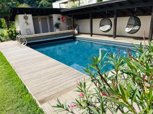 a swimming pool with a wooden deck next to a house at Rosalie Apartments in Lana