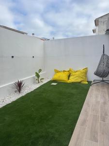 a patio with green grass and yellow pillows at Cantinho do Avô Almeida in Nazaré