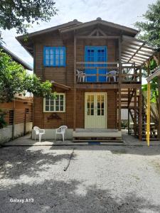 a wooden house with two white chairs in front of it at Residencial Álacre casa e cabana aluguel Ferrugem SC in Garopaba