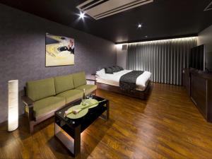 a bedroom with a bed and a couch and a table at HOTEL BYAKKA 岐阜 -Gifu- in Gifu