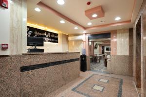 a lobby with a bar with a tv on the wall at Elyasmene in Qinā