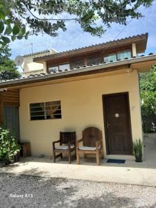 a house with two chairs and a door at Residencial Álacre casa e cabana aluguel Ferrugem SC in Garopaba