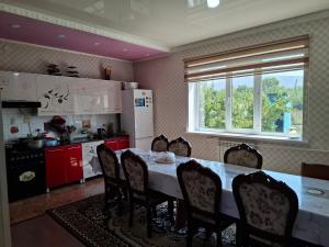 a kitchen with a table and chairs and a window at Aihan guest house in Pokrovka