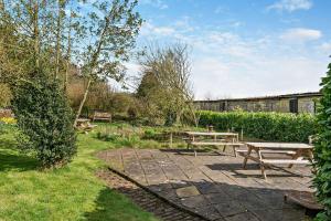 a picnic table and benches in a garden at Magpie Cottage in Newton