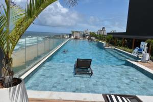 a swimming pool with a chair and the beach at Art Studio - Unidade Diferenciada in Salvador