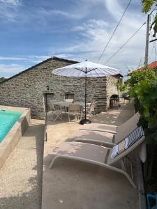 a patio with a table and an umbrella and a pool at Casa da Miquinhas in Murça