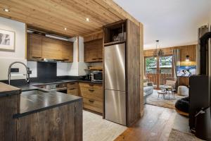 a kitchen with a stainless steel refrigerator and wooden cabinets at Appartement 4 à la Ferme des Lanches au Praz in Courchevel