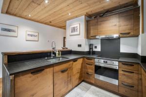 a kitchen with wooden cabinets and a sink at Appartement 4 à la Ferme des Lanches au Praz in Courchevel +34 photos