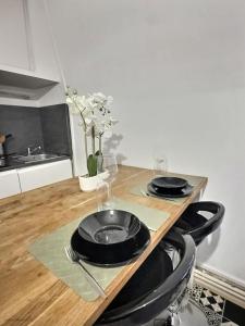 a table with two black plates on top of it at Superbe studio Cosy pour une ESCAPADE au Coeur de Senlis-Idéal pour Couples Voyageurs & Professionnels in Senlis +3 photos