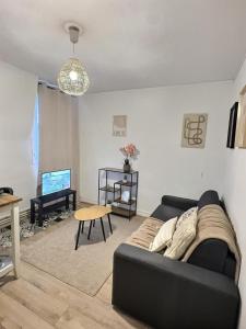 a living room with a black couch and a table at Superbe studio Cosy pour une ESCAPADE au Coeur de Senlis-Idéal pour Couples Voyageurs & Professionnels in Senlis