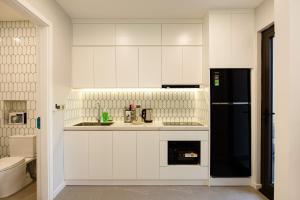 a kitchen with white cabinets and a black refrigerator at Nagomi Apartment in Hanoi +126 photos