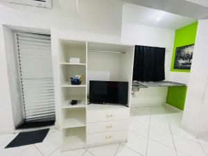 a living room with a tv and white shelves at Vista Bela Hotel in Pindamonhangaba