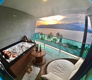 a room with a tub with a view of the ocean at Suites na Casa da Praia in Ilhabela