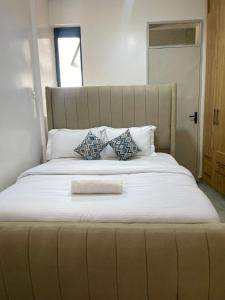1 cama blanca grande con cabecero grande y almohadas en Luxury Apartments, en Nairobi 5 fotos más