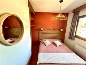 a small bedroom with a bed and a mirror at Bel Appartement 6 personnes au pied des pistes in Chamrousse