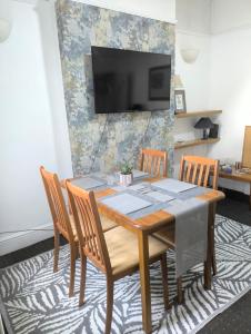 a dining room table with chairs and a television on a wall at City Vacations Kettering free WiFi for ' Short & Long stays ' Shared bathroom & Shared Kitchen Single room for 1 Adult in Kettering