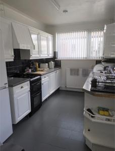 a white kitchen with white cabinets and black appliances at City Vacations Kettering free WiFi for ' Short & Long stays ' Shared bathroom & Shared Kitchen Single room for 1 Adult in Kettering