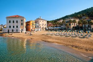 a beach with chairs and umbrellas and the water at Hotel La Pergola in Santa Maria di Castellabate