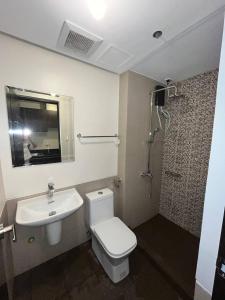 a bathroom with a toilet and a sink and a shower at Aurora Escalades Residences in Manila