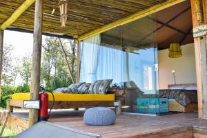 a bedroom with a yellow bed on a porch at Ole-lekurruki Naromoru Cabins in Naro Moru