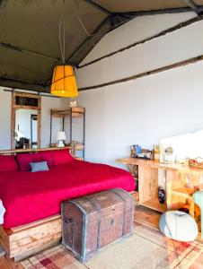 a bedroom with a red bed with a wooden trunk at Ole-lekurruki Naromoru Cabins in Naro Moru