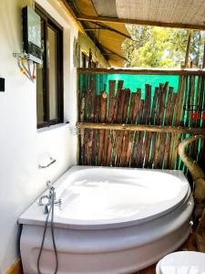 a white tub in a bathroom with a window at Ole-lekurruki Naromoru Cabins in Naro Moru
