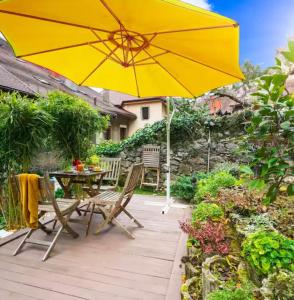 a patio with a table and a yellow umbrella at High Gardens Grand jardin en vieille ville in Annecy