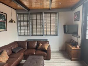 a living room with a brown couch and a flat screen tv at The workshop in King's Lynn