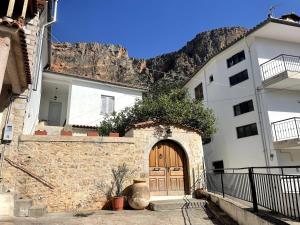 a white building with a wooden door and a mountain at Το σπίτι του Καντήλα in Leonidion