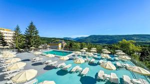 una grande piscina con sedie e ombrelloni di Hotel Germisara a Geoagiu Băi