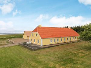a large yellow house with an orange roof on a field at 16 person holiday home in Nykøbing M in Jørsby