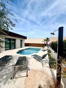 a swimming pool with two lounge chairs next to a house at Villa Luxury Jevarò - Peschiera del Garda in Peschiera del Garda