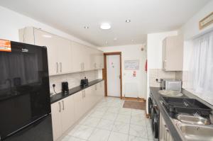 a kitchen with white cabinets and a black appliances at JMG House - West Bromwich in West Bromwich