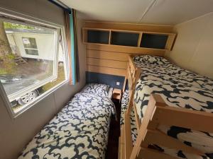 ein kleines Zimmer mit 2 Etagenbetten und einem Fenster in der Unterkunft Le Gewurz - Bungalow climatisé avec TV pour 5 in Boofzheim + 15 Fotos