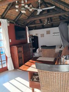 ein Wohnzimmer mit einem Tisch und einem Deckenventilator in der Unterkunft Pelican Place Guest Cottages in Durbanville
